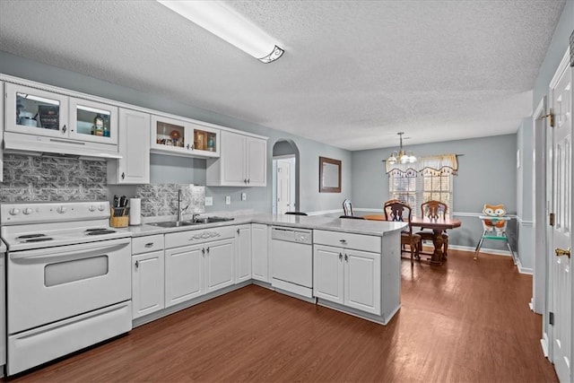 kitchen with white appliances, white cabinets, sink, hanging light fixtures, and kitchen peninsula