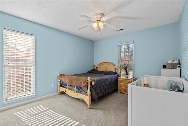 carpeted bedroom featuring ceiling fan and a textured ceiling