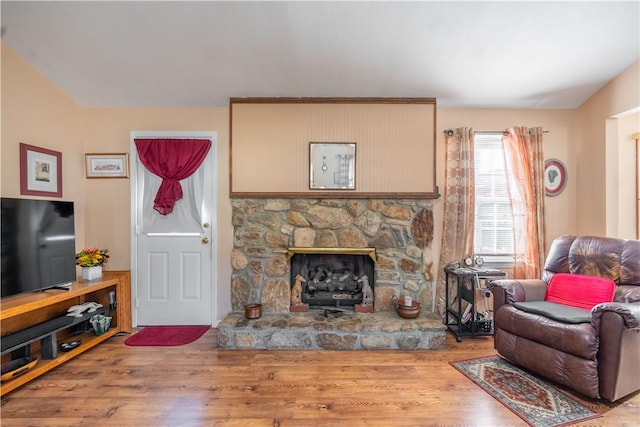 living room featuring hardwood / wood-style floors and a stone fireplace