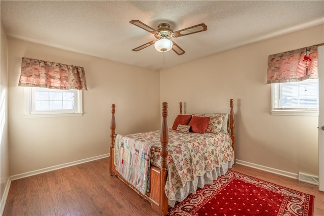 bedroom featuring hardwood / wood-style flooring, ceiling fan, a textured ceiling, and multiple windows