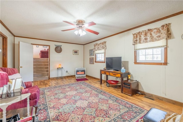 living room with a textured ceiling, heating unit, ceiling fan, crown molding, and hardwood / wood-style flooring