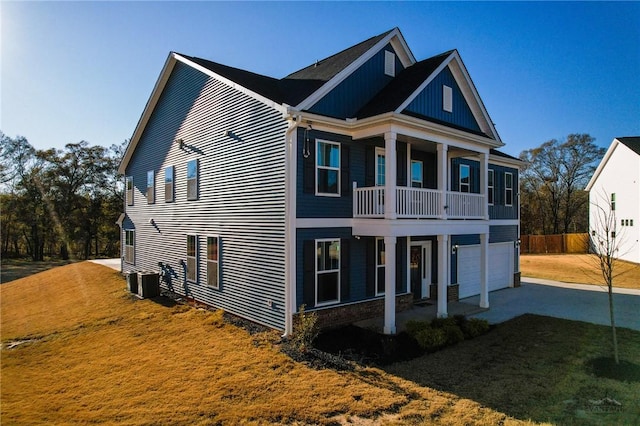 view of front of property with central AC unit, a garage, a balcony, and a front lawn