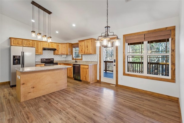 kitchen with vaulted ceiling, sink, black appliances, decorative light fixtures, and a center island