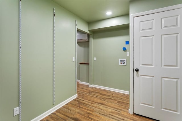 laundry room with a wall unit AC, hookup for a washing machine, and light hardwood / wood-style flooring