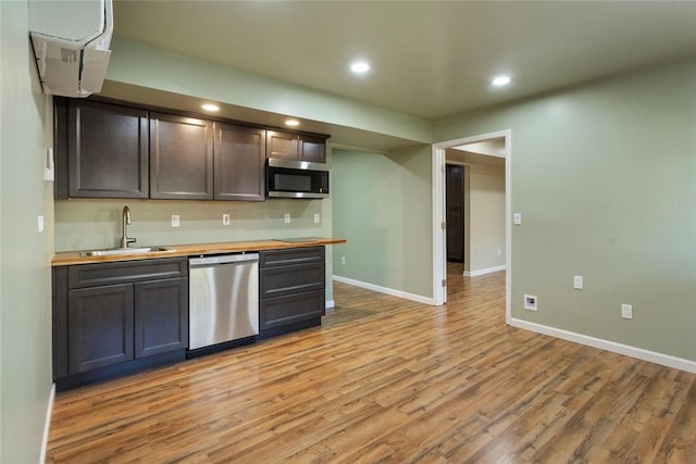 kitchen featuring dark brown cabinetry, sink, stainless steel appliances, light hardwood / wood-style flooring, and wooden counters