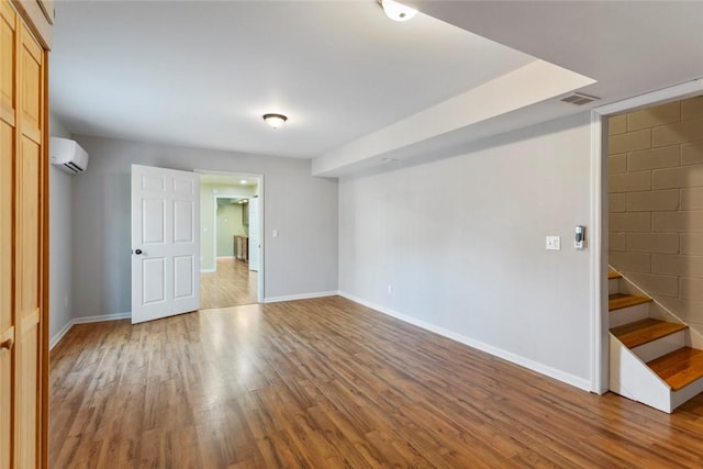 unfurnished room featuring hardwood / wood-style floors and a wall mounted AC