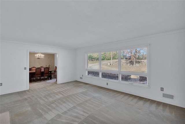 spare room with light carpet, ornamental molding, and a notable chandelier