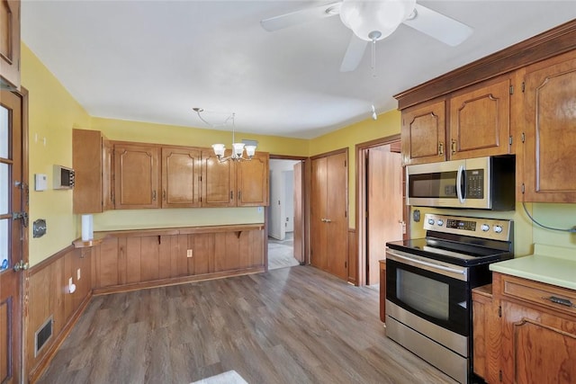 kitchen featuring decorative light fixtures, light wood-type flooring, stainless steel appliances, and ceiling fan with notable chandelier