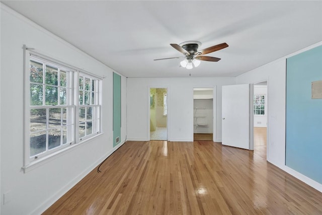 unfurnished bedroom with light wood-type flooring, connected bathroom, ceiling fan, and a walk in closet