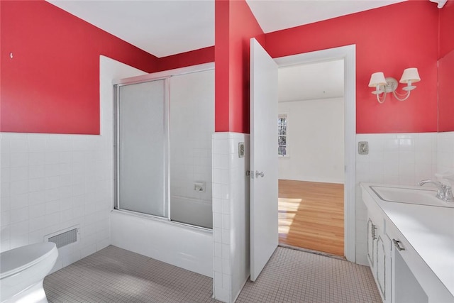 full bathroom with vanity, enclosed tub / shower combo, tile walls, and toilet