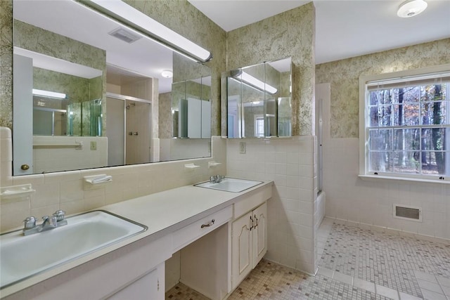 bathroom featuring tile patterned flooring, vanity, shower / bath combination with glass door, and tile walls