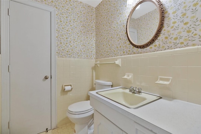 bathroom featuring vanity, toilet, and tile walls