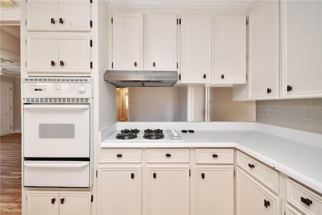 kitchen featuring white cabinets, wood-type flooring, white appliances, and decorative backsplash