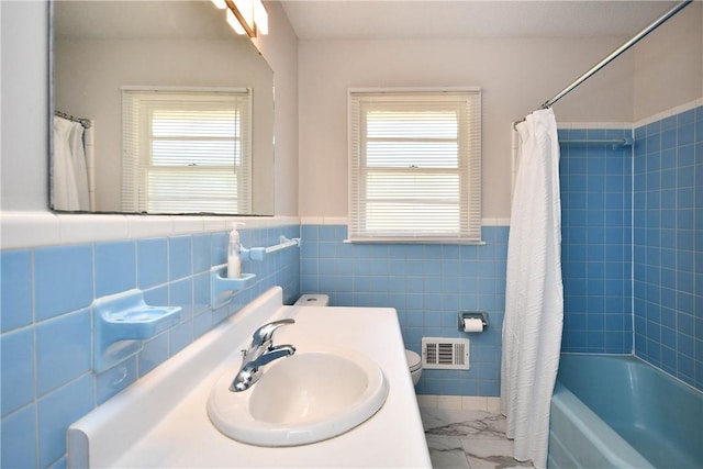 full bathroom featuring toilet, shower / tub combo with curtain, tile walls, and sink