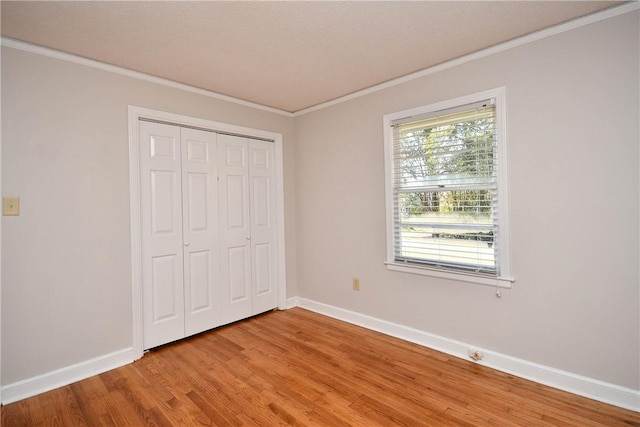 unfurnished bedroom featuring a textured ceiling, a closet, crown molding, and light hardwood / wood-style flooring