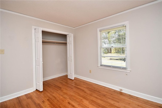 unfurnished bedroom featuring a textured ceiling, hardwood / wood-style flooring, a closet, and ornamental molding