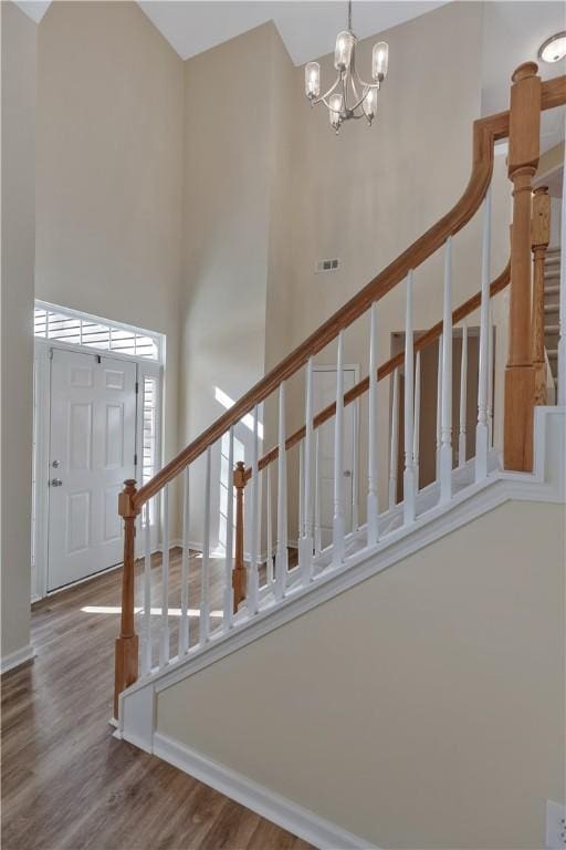 stairs with hardwood / wood-style floors, a high ceiling, and a notable chandelier