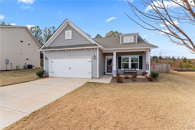 view of front of home with a porch, a front lawn, central AC unit, and a garage