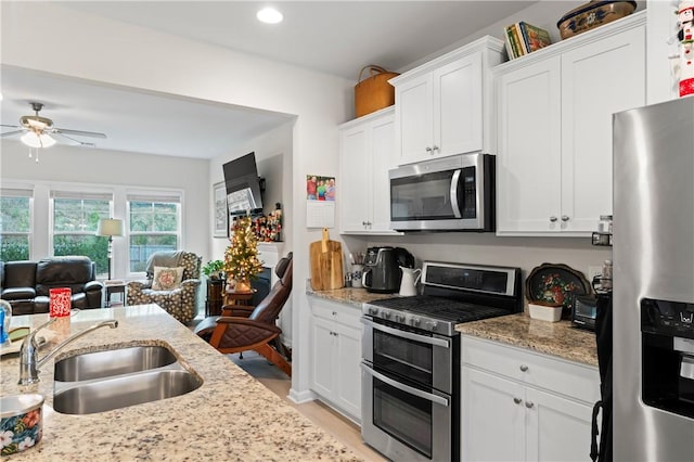 kitchen with ceiling fan, sink, appliances with stainless steel finishes, white cabinets, and light wood-type flooring