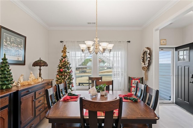 dining area with light hardwood / wood-style floors, ornamental molding, and an inviting chandelier