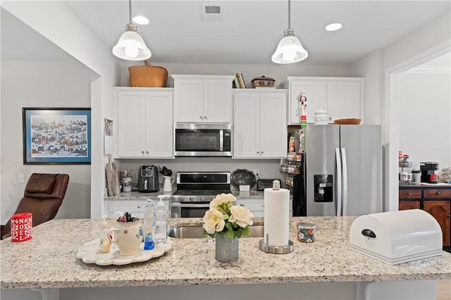 kitchen featuring light stone countertops, appliances with stainless steel finishes, white cabinetry, and pendant lighting