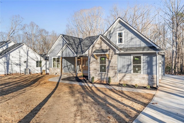 view of front of house with stone siding, a shingled roof, and board and batten siding