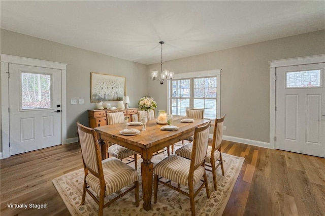 dining area with wood-type flooring and a chandelier