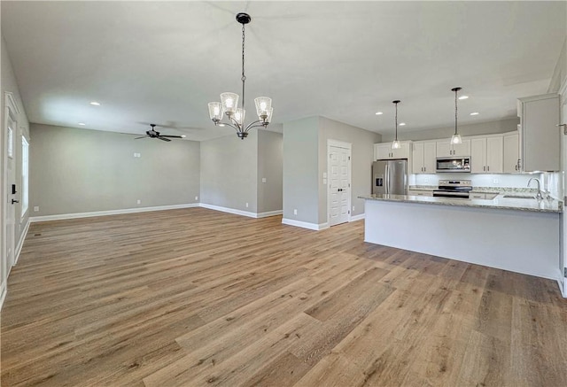 kitchen with white cabinetry, light hardwood / wood-style floors, decorative light fixtures, and appliances with stainless steel finishes