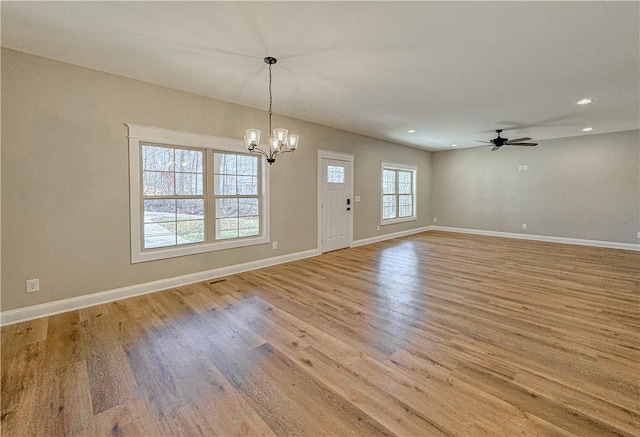 interior space featuring ceiling fan with notable chandelier and light wood-type flooring