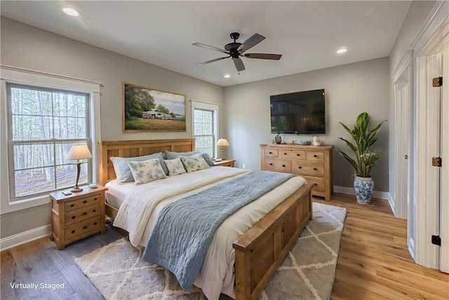 bedroom featuring ceiling fan, light wood-type flooring, and multiple windows