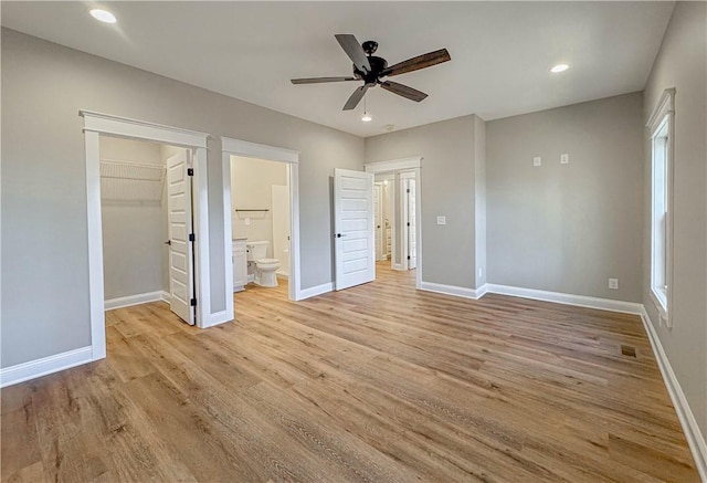 unfurnished bedroom with a walk in closet, ceiling fan, connected bathroom, light hardwood / wood-style floors, and a closet