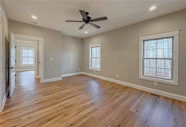 empty room with ceiling fan, a healthy amount of sunlight, and light wood-type flooring