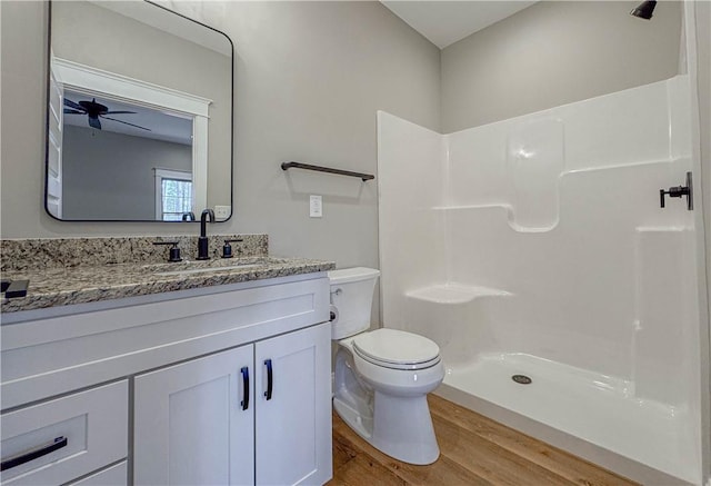 bathroom featuring ceiling fan, walk in shower, toilet, vanity, and hardwood / wood-style flooring