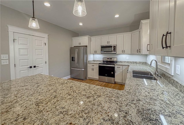 kitchen with pendant lighting, sink, light hardwood / wood-style floors, white cabinetry, and stainless steel appliances