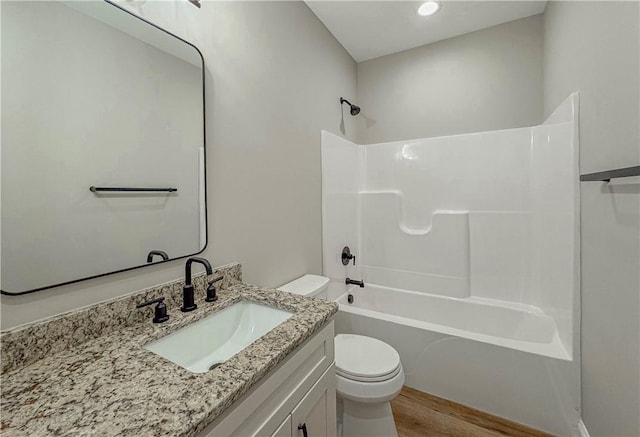 full bathroom with shower / bathing tub combination, vanity, hardwood / wood-style flooring, and toilet