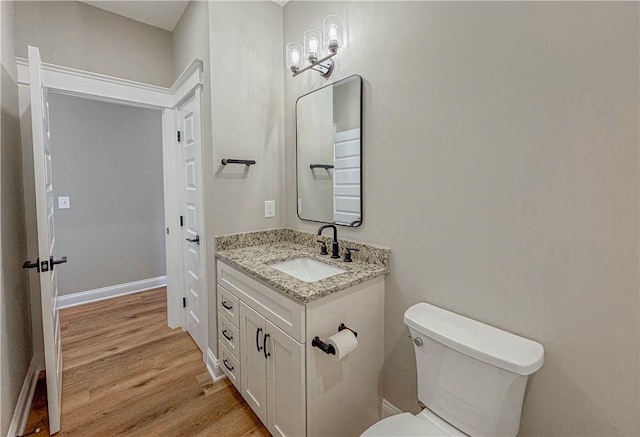 bathroom featuring vanity, wood-type flooring, a notable chandelier, and toilet