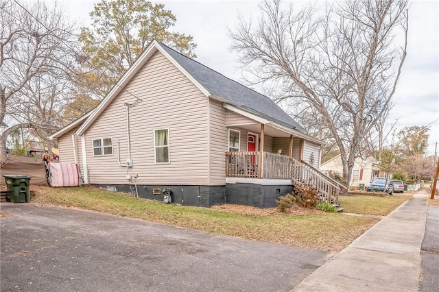 view of side of property featuring covered porch and a yard