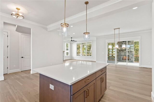 kitchen featuring light wood-type flooring, decorative light fixtures, a kitchen island, and ceiling fan