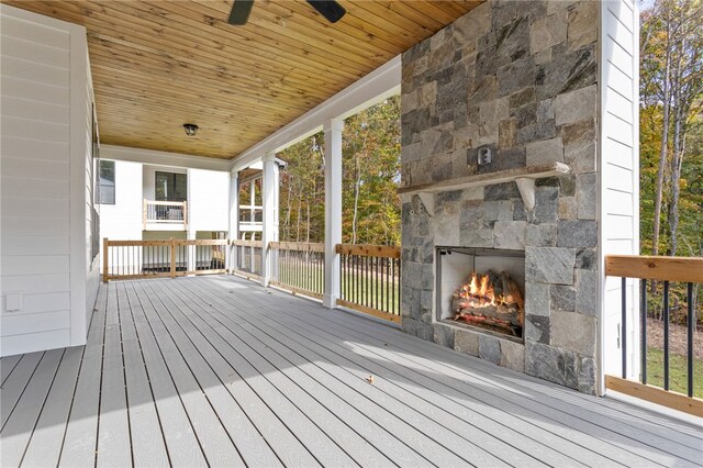 wooden deck featuring an outdoor stone fireplace and ceiling fan