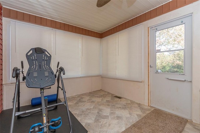 exercise area featuring ceiling fan and wood walls