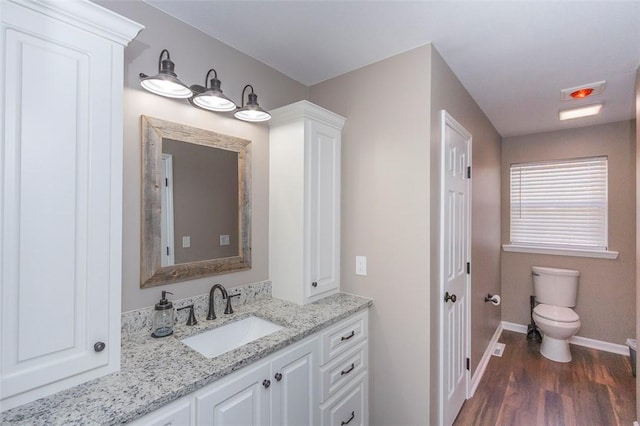 bathroom with toilet, vanity, and hardwood / wood-style flooring