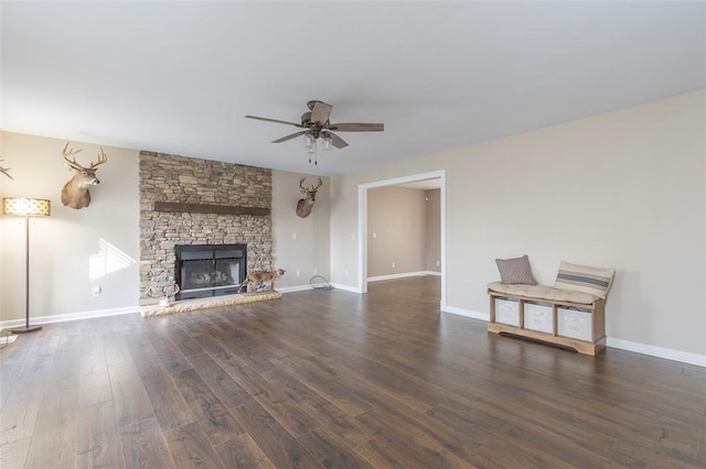 unfurnished living room featuring a stone fireplace, ceiling fan, and dark wood-type flooring