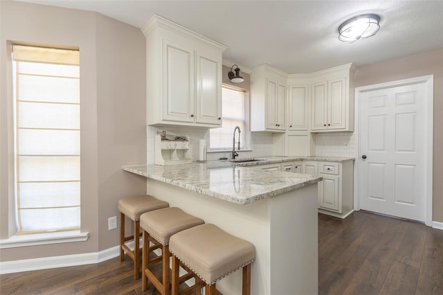 kitchen featuring a breakfast bar, sink, white cabinets, and dark hardwood / wood-style flooring