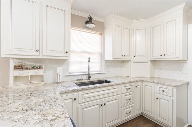 kitchen with white cabinets, tasteful backsplash, crown molding, and sink