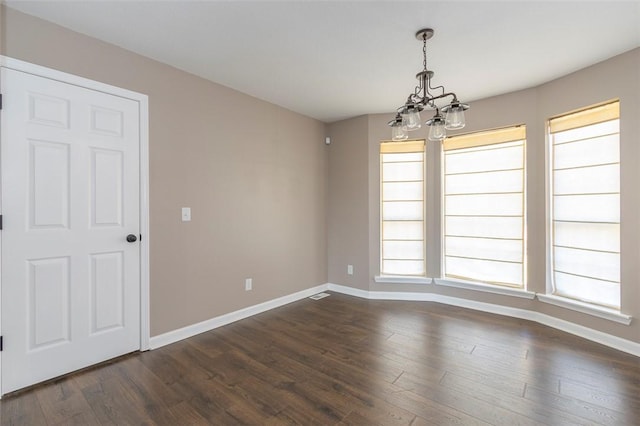 unfurnished room featuring dark hardwood / wood-style floors and an inviting chandelier