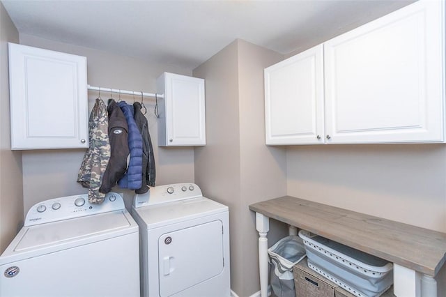 clothes washing area featuring washing machine and dryer and cabinets