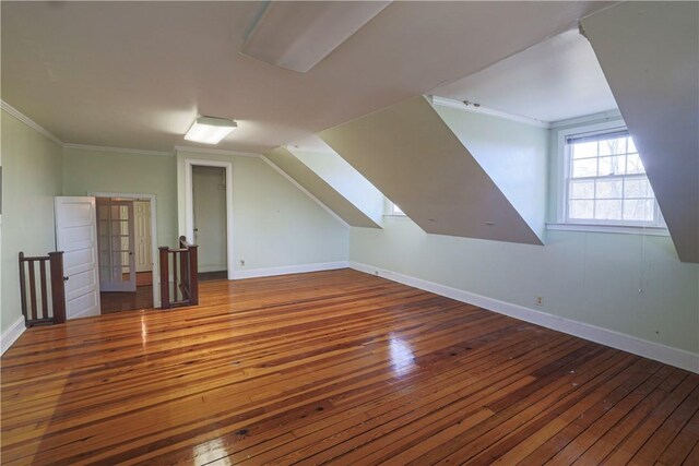 additional living space with vaulted ceiling, wood finished floors, and baseboards