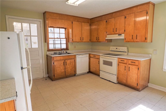 kitchen featuring under cabinet range hood, white appliances, light countertops, brown cabinets, and light floors