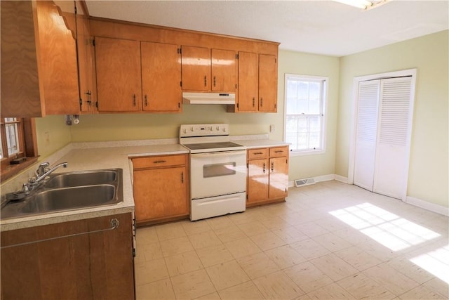 kitchen with white range with electric cooktop, brown cabinets, light countertops, under cabinet range hood, and a sink