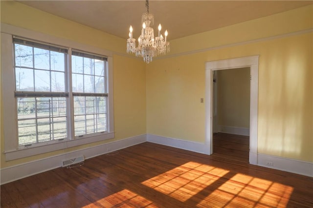 spare room featuring dark wood finished floors, visible vents, and a healthy amount of sunlight